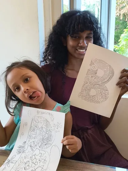 A duplicate image of a student and instructor having fun showing off their intricate zentangle letter 'B' drawings.