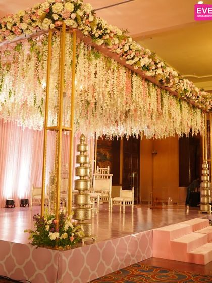 A close-up of the pastel pink mandap, showing the delicate hanging wisteria and floral arrangements. This design is perfect for couples looking for a romantic and elegant wedding ceremony setup.