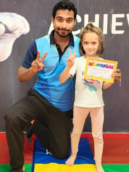 This student proudly displays her certificate, marking her successful completion of a new skill level in our gymnastics program.