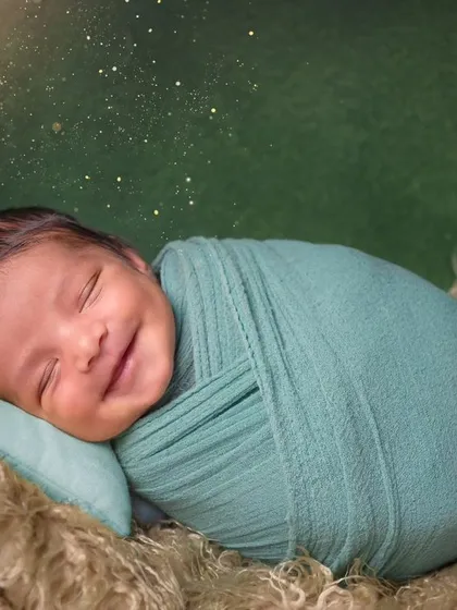 That heart-melting newborn smile. This little one is happily dreaming, swaddled snugly in a cozy nest. Capturing these fleeting smiles is what makes newborn photography so special.