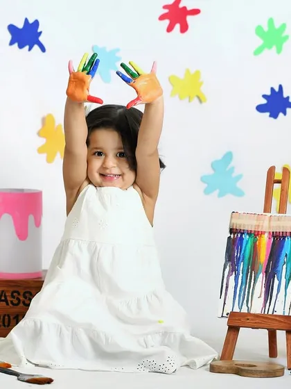A little artist showing off her colorful hands. This painter theme is a great sensory experience for toddlers and results in vibrant, joyful photos.