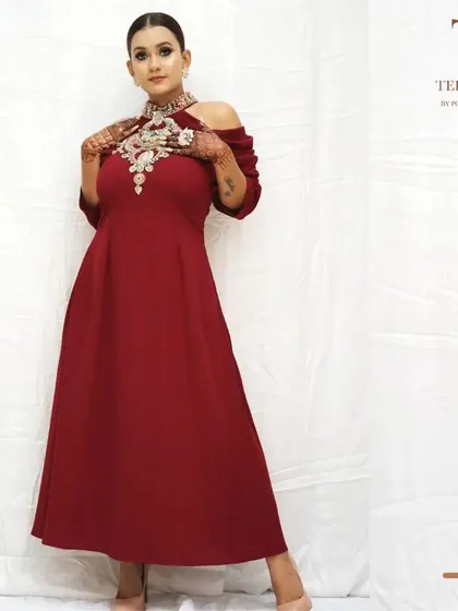 This off-shoulder maroon gown is a perfect example of modern elegance. The statement neckline is heavily embellished, making it a standout piece for any festive occasion or formal event.