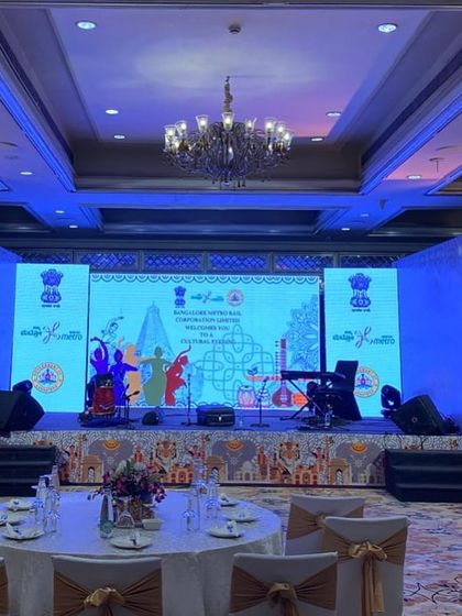 A full view of the stage and seating for the BMRCL cultural evening. The setup includes a large LED screen, thematic side panels featuring peacocks, and carefully arranged lighting to create a refined ambiance.
