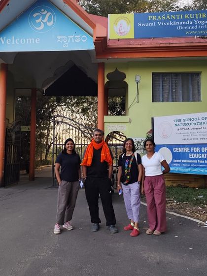 Our team at the entrance of Prashanti Kutiram, SVYASA University. These experiences are about learning, bonding, and living yoga beyond the classroom.