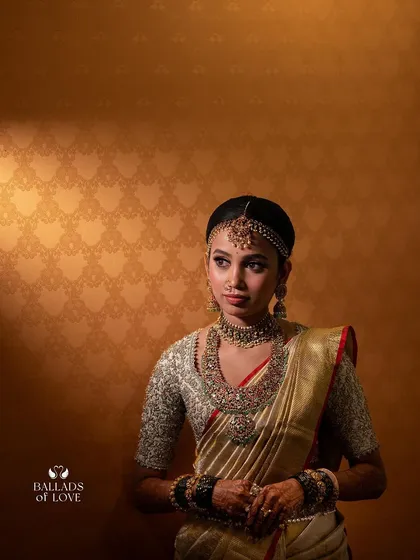 A duplicate of image 95, showing a beautifully lit portrait of a bride in her gold saree. The intricate details of her custom embroidered blouse are clearly visible.