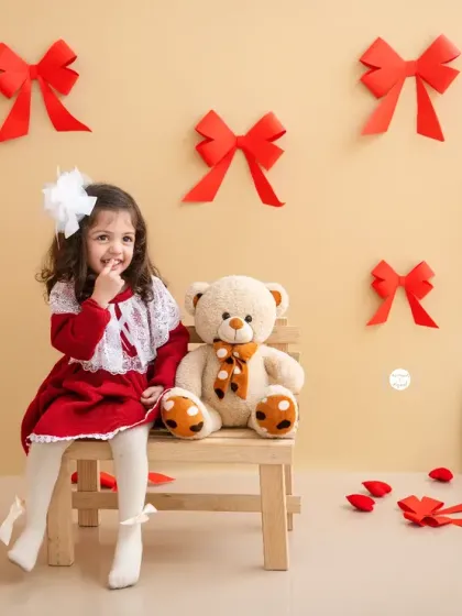 A sweet and slightly mischievous smile from this little Valentine, sitting with her best teddy bear friend.