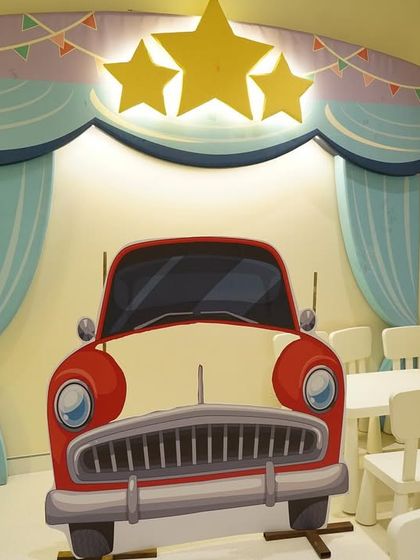 A vintage car photo booth prop and dedicated seating area for a toddler's car-themed birthday party.