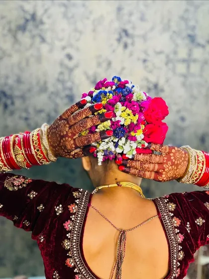 "Main toh saj gayi re sajna ke liye." A bride's hands framing her beautiful floral hairstyle, a perfect shot of joy and anticipation.
