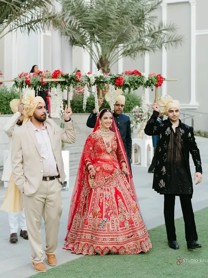 The bride's grand entrance under a beautiful floral 'phoolon ki chadar' held by her brothers.