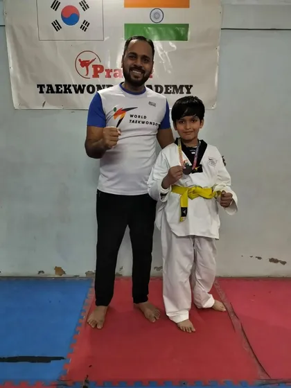 A yellow belt fighter posing with his medal after the district competition.