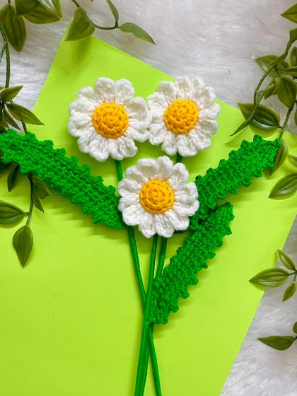 A simple, beautiful shot of the crochet daisies with their bright yellow centers and delicate white petals, ready to be added to a bouquet.