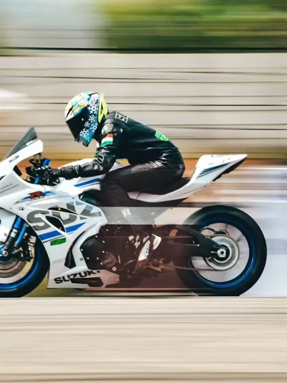 A white Suzuki superbike, custom-built for the drag strip, captured in a perfect motion blur. The extended swingarm is a classic modification for maximum straight-line stability.