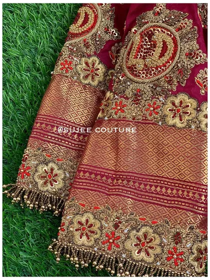 A detailed close-up of the sleeve, highlighting the custom initial embroidery. The combination of the Kanchipuram fabric border and the intricate handwork makes this piece truly special.