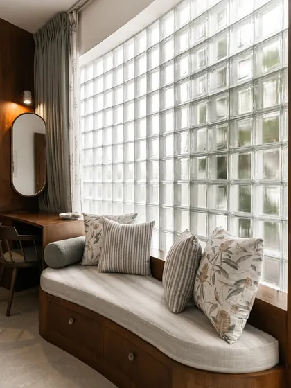 A close-up of the bedroom window seat, showcasing the soft upholstery and patterned cushions. The curved wooden frame and built-in storage make this a beautiful and practical feature.