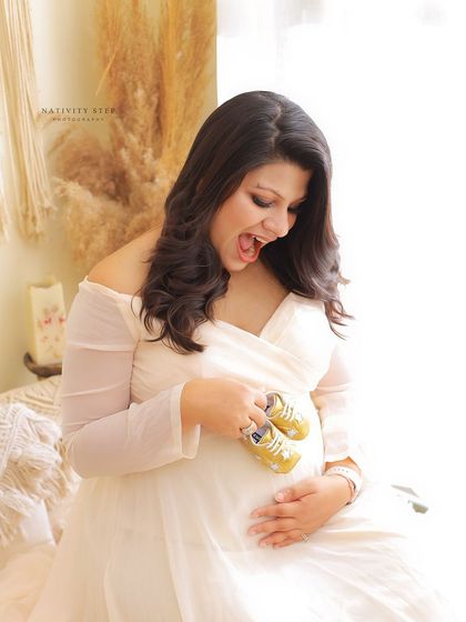 A joyful and candid moment in our Boho setup. The mother-to-be's excited expression as she looks at the baby shoes is priceless.