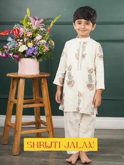 This little boy is ready for his photo-op in an off-white kurta featuring a playful potli print. It's a unique design that adds a touch of fun.