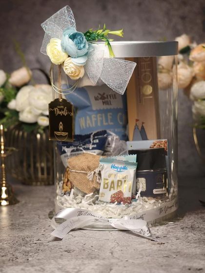 Another modern take on Diwali gifting. This acrylic jar hamper is filled with a curated selection of snacks and goodies, finished with a beautiful floral-tied ribbon.