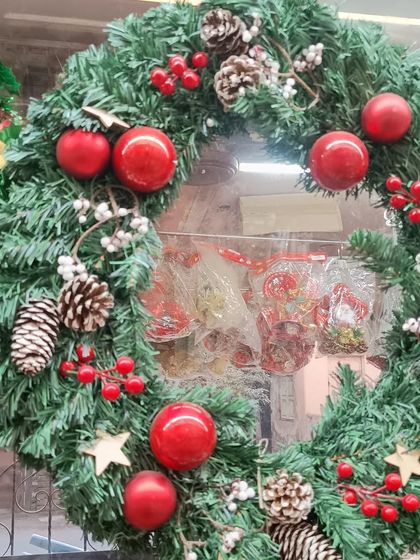 A classic Christmas wreath, lush and green, decorated with red baubles, pinecones, and berries. This is a timeless piece of holiday decor, perfect for your front door or as a centerpiece.