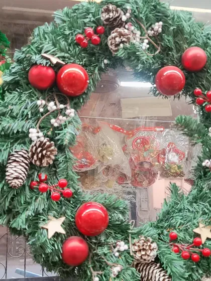 A classic Christmas wreath, lush and green, decorated with red baubles, pinecones, and berries. This is a timeless piece of holiday decor, perfect for your front door or as a centerpiece.