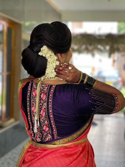 A view of her elegant bun hairstyle, adorned with jasmine flowers, showing that even short hair can be styled traditionally and beautifully.