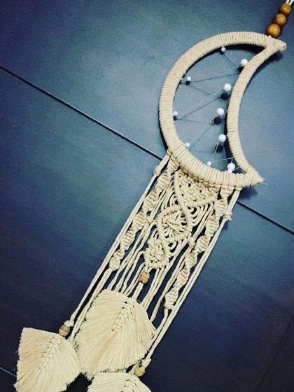 An angled shot of the moon dreamcatcher, showing the intricate knotting and the delicate feathers that hang below.