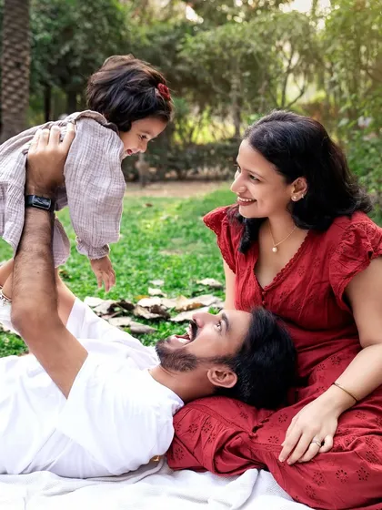 A perfect family picnic scene. This playful and loving interaction between mom, dad, and baby girl makes for a heartwarming and candid photograph.