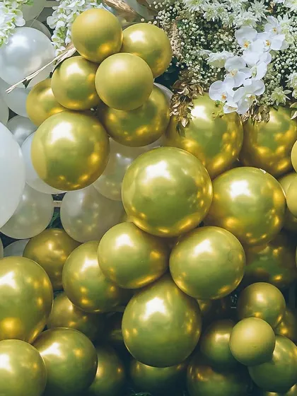 A detailed shot of a gold and white balloon garland. The clusters of metallic gold balloons add a pop of glamour, while the fresh white flowers provide a soft, organic touch to the overall design.