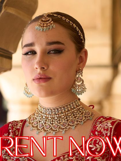 Step into your fairytale with our designer jewellery. This model showcases a beautiful pastel choker set that perfectly complements her red embroidered lehenga.