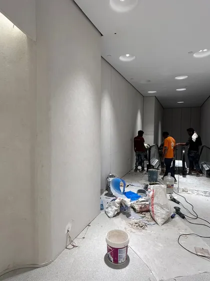 The early stages of plaster and finishing work near the escalators. This raw site image shows the beginning of the transformation from a concrete shell to a polished, high-end interior.