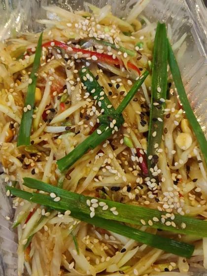 This is our Som Tam, a classic spicy raw papaya salad from Thailand. It's a refreshing and tangy dish with a mix of shredded papaya, chillies, peanuts, and a zesty dressing.