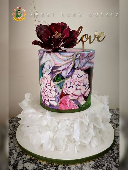 Art meets cake in this unique wedding design. The bottom tier features delicate, hand-applied wafer paper ruffles, while the top tier is hand-painted with a beautiful floral watercolor design. A single, dramatic sugar flower and a "love" topper complete this artistic statement piece.