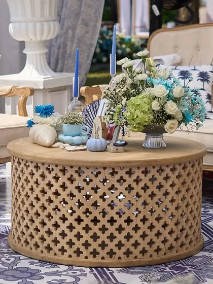 Another view of the chic lounge area, highlighting the carved wooden coffee table and the mix of patterned cushions.