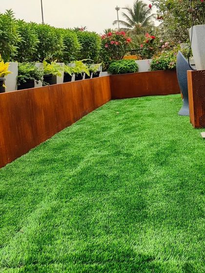 This rooftop lawn is bordered by a Corten steel planter. I ensure the turf remains healthy even in challenging environments like this, managing drainage and soil health for a perfect green carpet.