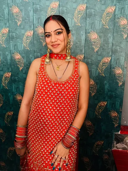 A close-up of the red sharara set, showing the detailed embroidery on the kurta and the matching choker-style necklace.