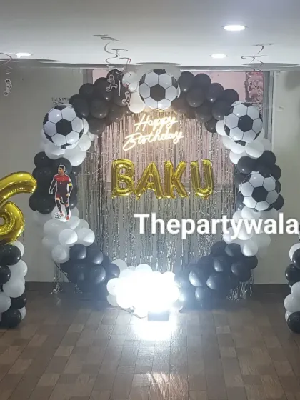 Goal! A fantastic football theme party with a full ring of black and white balloons, complete with football balloons. The silver shimmer backdrop and custom name in gold foil letters make it a winner.