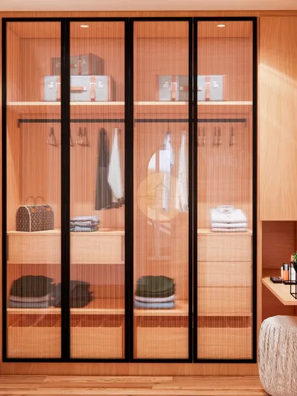 This custom wardrobe features fluted glass doors with sleek black frames, offering a sophisticated and modern storage solution. The design includes dedicated sections for hanging clothes, drawers, and open shelving for luggage.