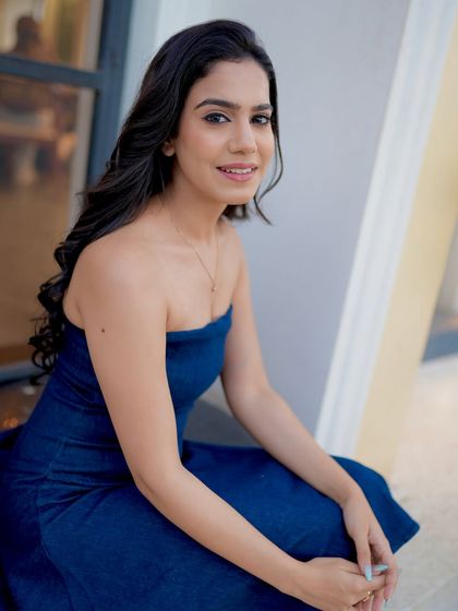 A seated pose in the blue dress, looking friendly and engaging.