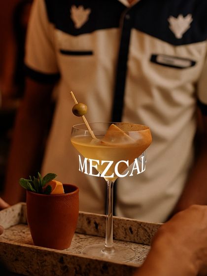 A beautifully crafted mezcal cocktail, served on a tray at the Agave Bar. Smoky, smooth, and utterly captivating.