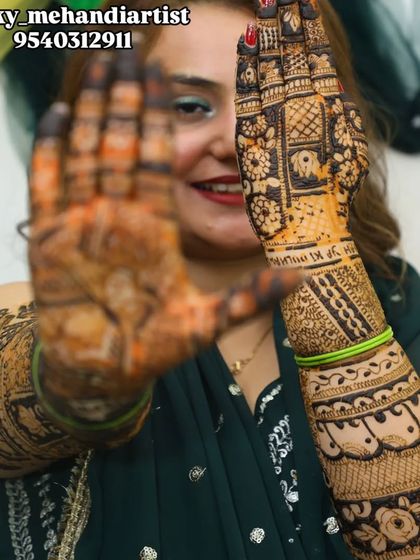 A creative pose from a happy bride, peeking through her beautifully hennaed hands.