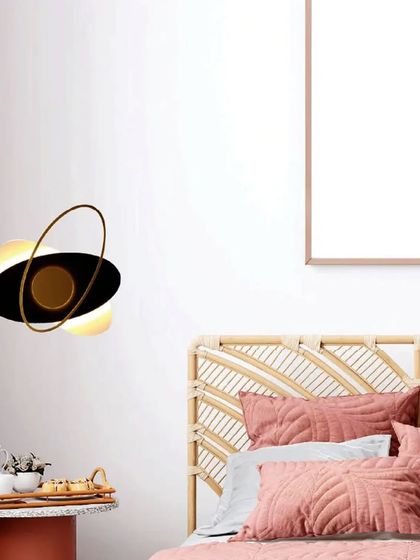 An orbital-themed wall sconce adds a playful yet sophisticated charm to this bedroom. The design provides a warm, ambient light that complements the room's soft and cozy aesthetic.