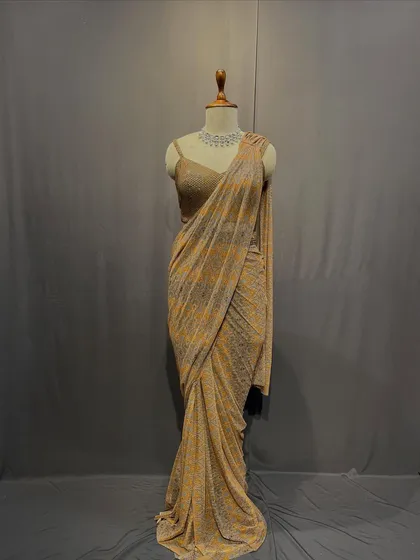 A shimmering gold and beige drape saree that catches the light beautifully. This piece is perfect for making a subtle yet glamorous statement.