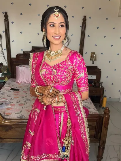 A full, happy smile from the bride. The nude glossy pout adds a touch of modern elegance to her traditional pink outfit.