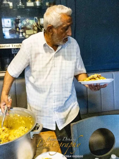 A host serving food to our team. The hospitality we receive at local clubs across the UK is always exceptional.