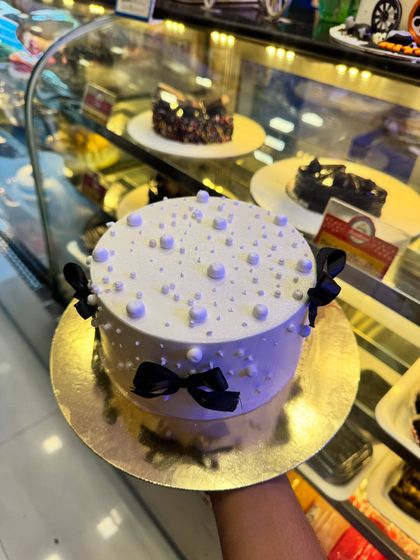 A chic and simple cake with black bows and white pearl sprinkles. This design is elegant and modern, perfect for a sophisticated celebration.