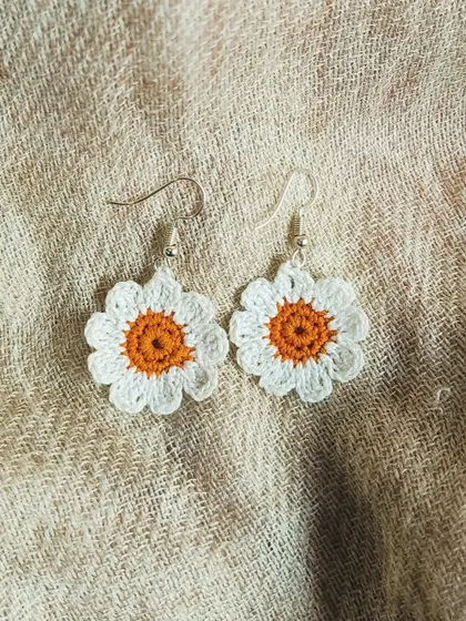 Simple and sweet, these little daisy earrings are perfect for everyday wear. The white petals and orange center are crocheted from soft cotton thread.