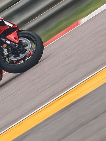 A motion-blurred shot capturing the immense speed of a Ducati superbike as it flies past on the track.