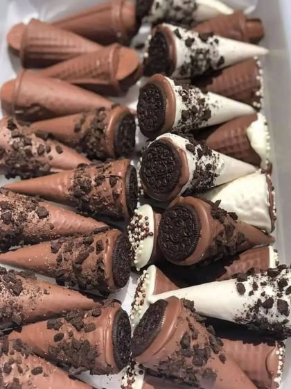 A tray of my homemade chocolate-dipped ice cream cones. I offer cones dipped in milk chocolate with chocolate chips and white chocolate with Oreo crumbles, perfect for a quick and delicious treat.