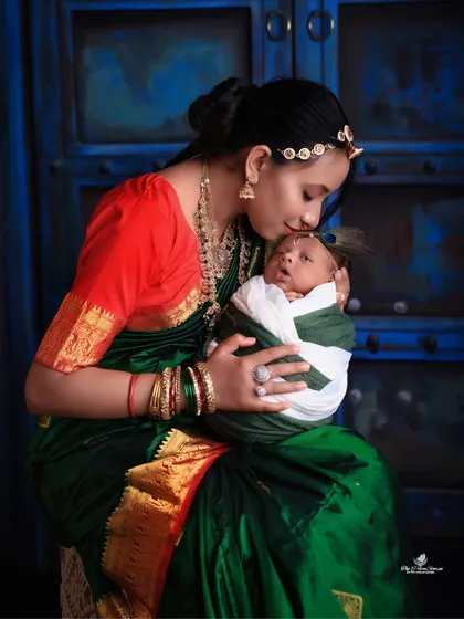 A duplicate of a beautiful moment, this image captures the deep connection between a mother and her newborn, dressed in traditional attire for a festive photoshoot.