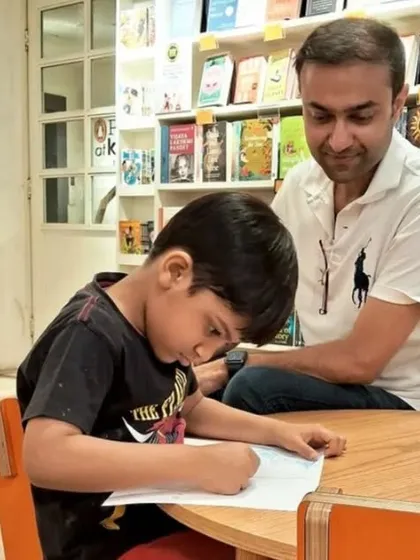 A father helps his son with a drawing, a simple and precious moment. Our store is designed to encourage these quiet, shared activities.