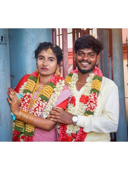 A relaxed portrait of the couple after their temple ceremony. They are standing by a traditional blue wall, and their happy smiles show the beginning of their new life together.
